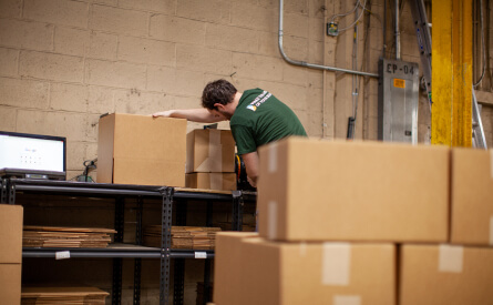 Warehouse manager packs and weighs boxes with books ordered by school